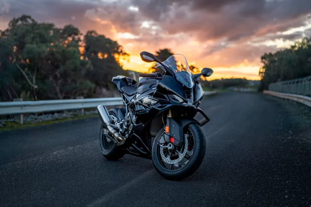 Motorcycle parked beside a guardrail at sunset
