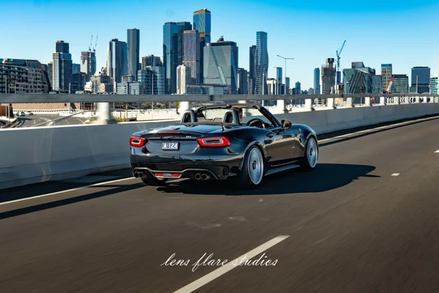 Dark sports car in motion against the Melbourne skyline